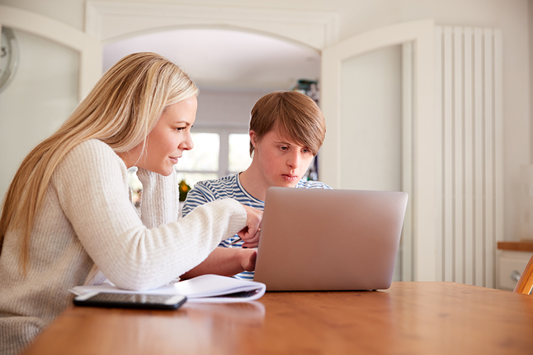 woman helping young man with something on the computer screen